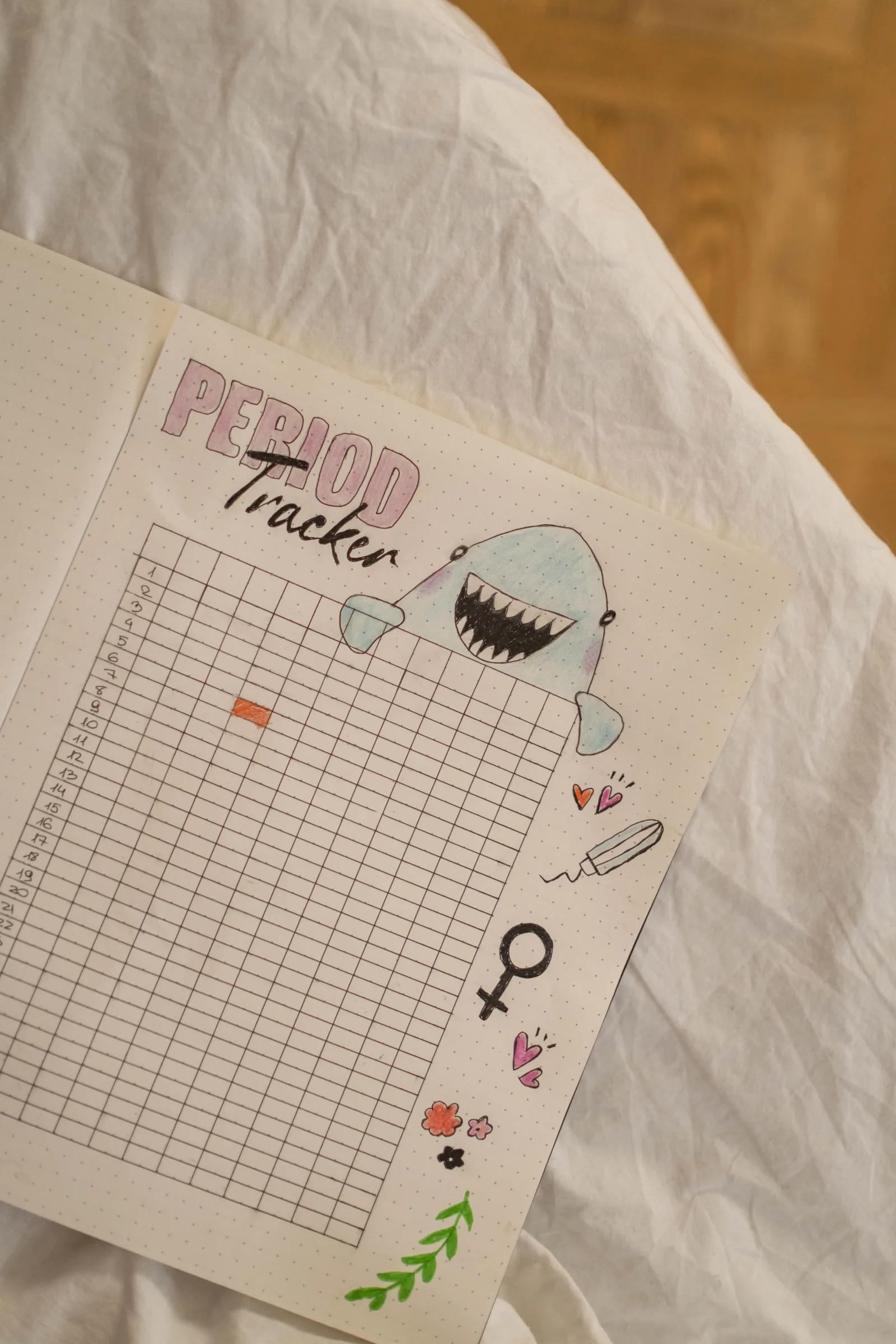 An illustrated menstrual cycle tracker in an open notebook.