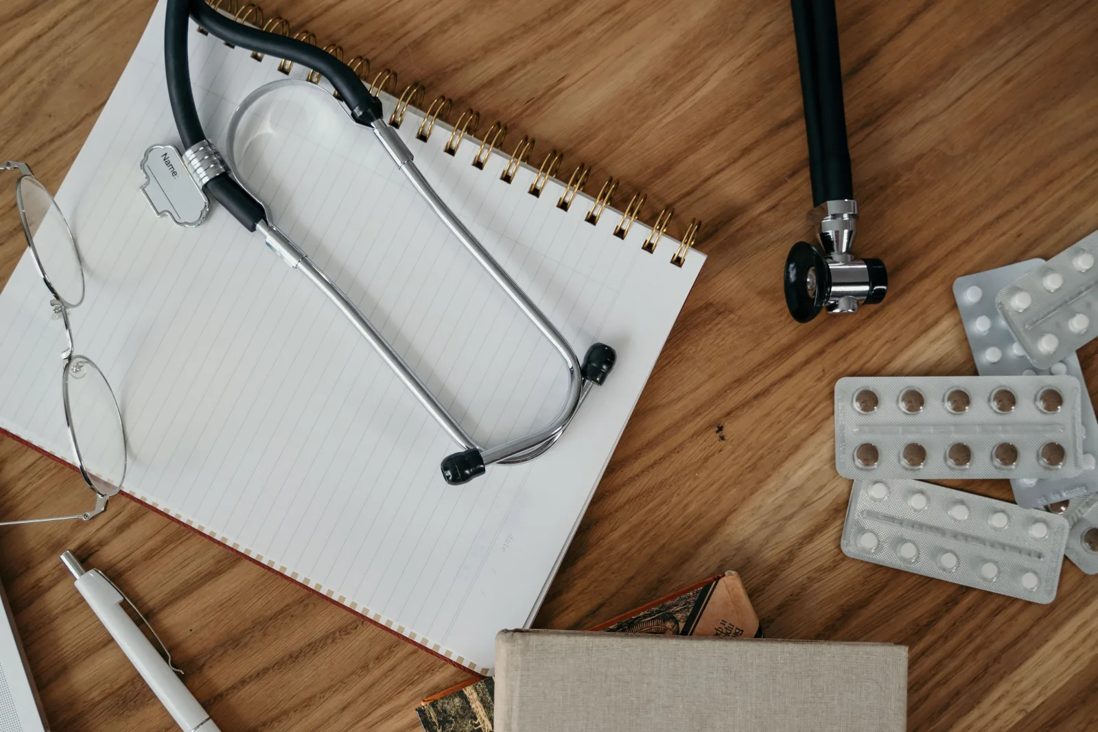 A stethoscope, notebook and medical supplies arranged on a desk.